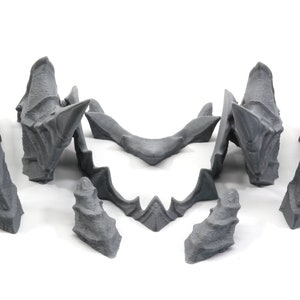 May include: A set of seven grey 3D printed plastic pieces that form a dragon head. The pieces are designed to be assembled together to create a complete dragon head.