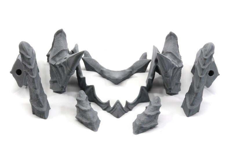 May include: A set of seven grey 3D printed plastic pieces that form a dragon head. The pieces are designed to be assembled together to create a complete dragon head.