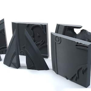 May include: Five gray, intricately carved, square-shaped tiles with a raised design. The tiles are arranged in a semi-circle on a white surface.