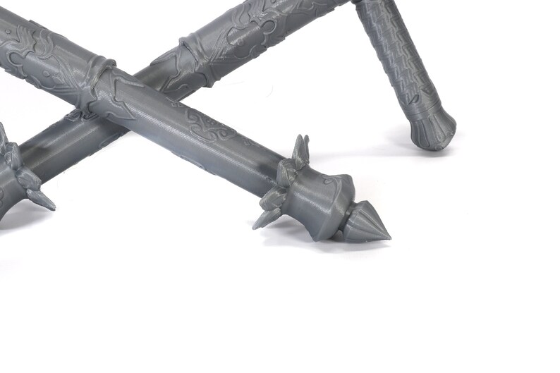 May include: Two gray, intricately detailed, 3D printed staffs with spiked ends.