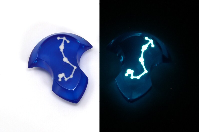 May include: A blue resin pendant with a white constellation design that glows in the dark.