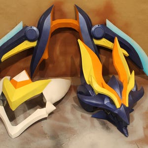 May include: Three pieces of a blue, yellow, and orange costume prop. The prop is made of foam and has a sharp, angular design.