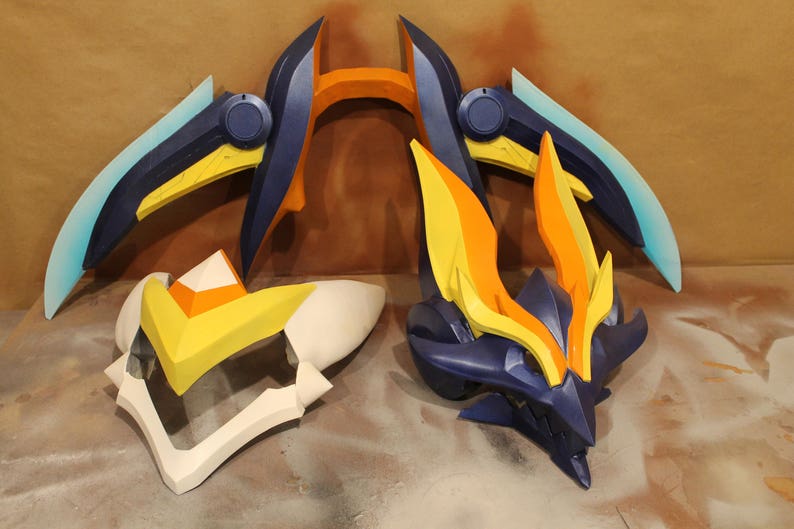 May include: Three pieces of a blue, yellow, and orange costume prop. The prop is made of foam and has a sharp, angular design.
