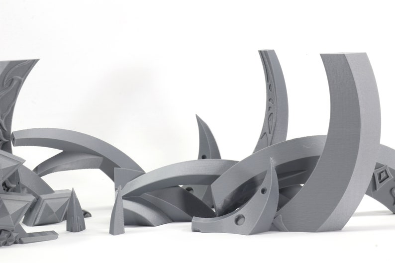 May include: A set of gray 3D printed plastic pieces that form a decorative design. The pieces are arranged in a random pattern and are made of a smooth, matte material.