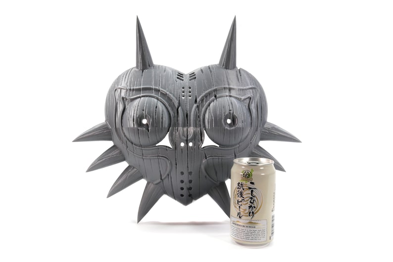 May include: A gray, heart-shaped mask with spikes and a textured surface. The mask is about the size of a can of soda.
