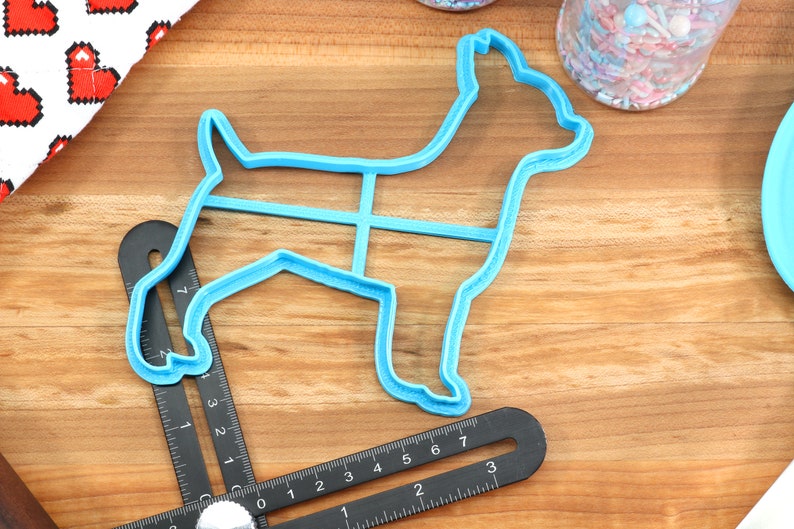 Puede incluir: Cortador de galletas de pl&aacute;stico azul con forma de perro. El cortador tiene un contorno detallado de un perro con una cola larga y orejas puntiagudas.
