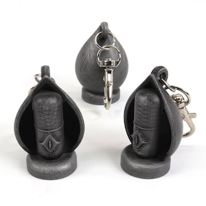 May include: Three silver-colored microphone keychain charms. Each charm is shaped like a microphone with a small eye design on the front. The charms are attached to silver key rings.