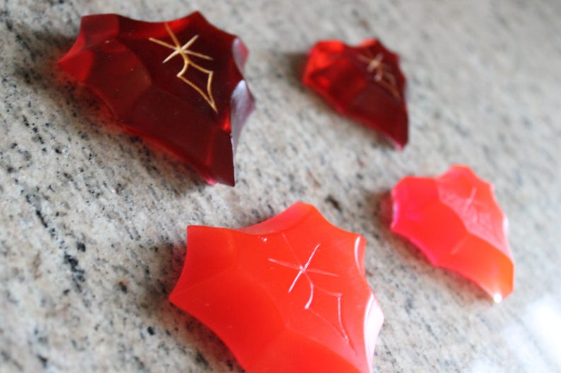 May include: Four red, star-shaped, translucent, decorative pieces with a gold design.