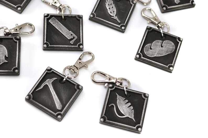 May include: A set of eight silver keychains with different symbols on each. The symbols include a hammer, a leaf, a wheat stalk, a cloud, a knife, and a helmet. The keychains are made of metal and have a silver finish.