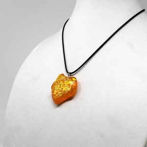 May include: A gold and orange heart-shaped pendant necklace on a black cord.