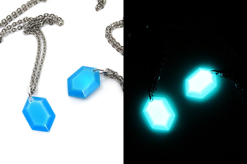 May include: Two necklaces with hexagonal glow-in-the-dark pendants. The pendants are blue in daylight and glow green in the dark.
