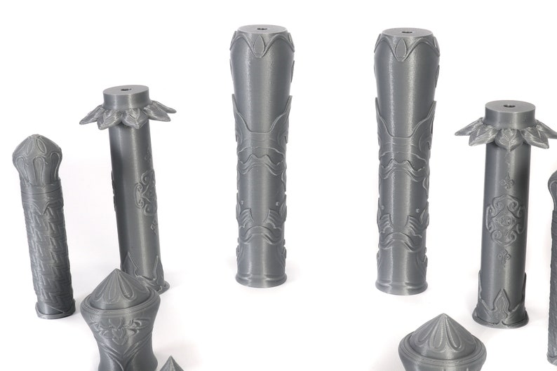 May include: A set of six gray 3D printed decorative columns with intricate designs. The columns are various sizes and shapes, with some having a flared top and others having a flat top.