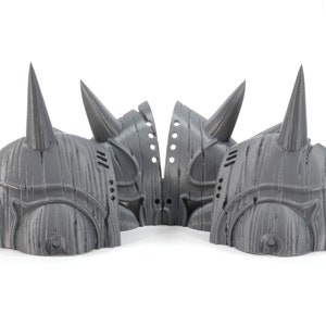 May include: Four gray 3D printed helmets with pointed horns. The helmets have a textured surface that resembles wood grain.