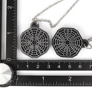 May include: Two silver necklaces with octagonal pendants featuring a geometric pattern. The pendants are about 2 inches in diameter.