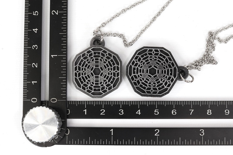 May include: Two silver necklaces with octagonal pendants featuring a geometric pattern. The pendants are about 2 inches in diameter.