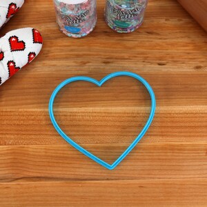 May include: A blue heart-shaped cookie cutter on a wooden surface.