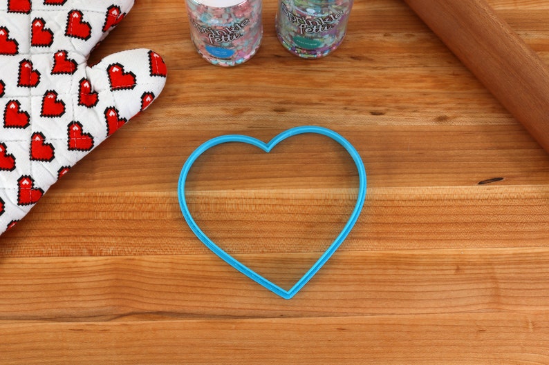 May include: A blue heart-shaped cookie cutter on a wooden surface.