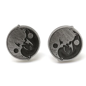 May include: A pair of silver cufflinks with a yin yang design featuring two stylized dragons facing each other.