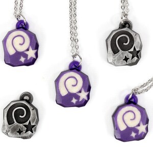 May include: Five necklaces with purple and silver pendants featuring a white spiral and two white stars. The pendants are shaped like a rock.