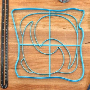 May include: A blue plastic mold shaped like a slice of bread with a swirl design inside. The mold is on a wooden surface.