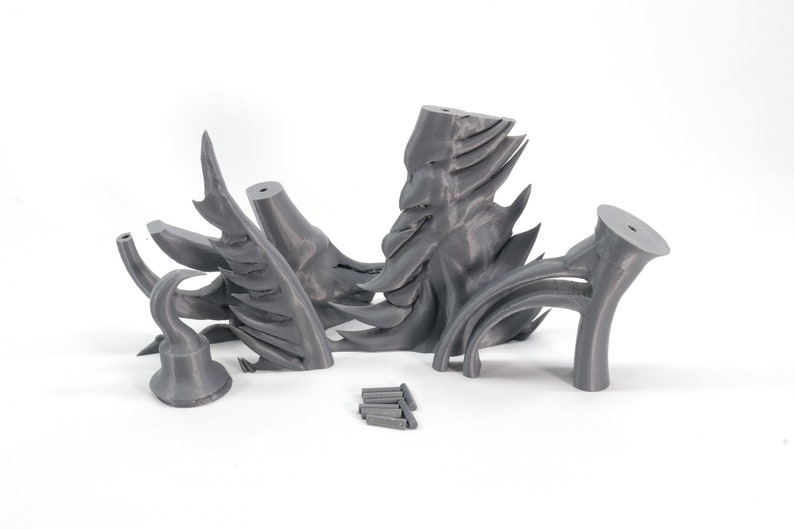 May include: A set of five gray 3D printed pieces that form a dragon sculpture. The pieces are arranged on a white surface.