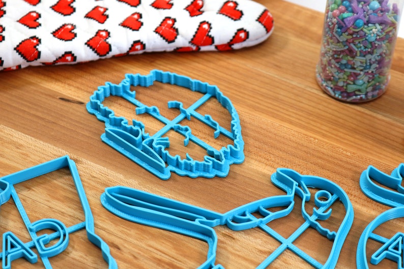 Puede incluir: Un juego de cortadores de galletas de pl&aacute;stico azul en varias formas, incluyendo un &aacute;rbol, un p&aacute;jaro y una letra "A".