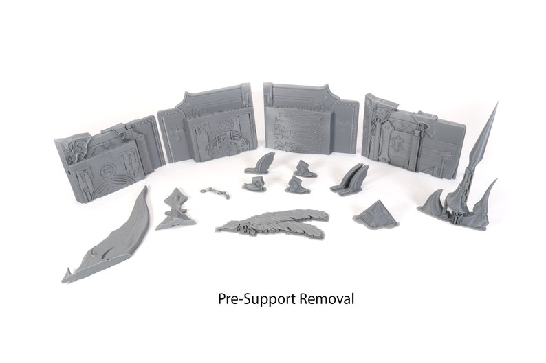 May include: A set of gray 3D printed pieces for a tabletop game or miniature. The pieces are in various shapes and sizes, including a large, ornate archway, a smaller archway, and several smaller pieces. The pieces are pre-support removal, meaning they have not yet been cleaned up after printing.