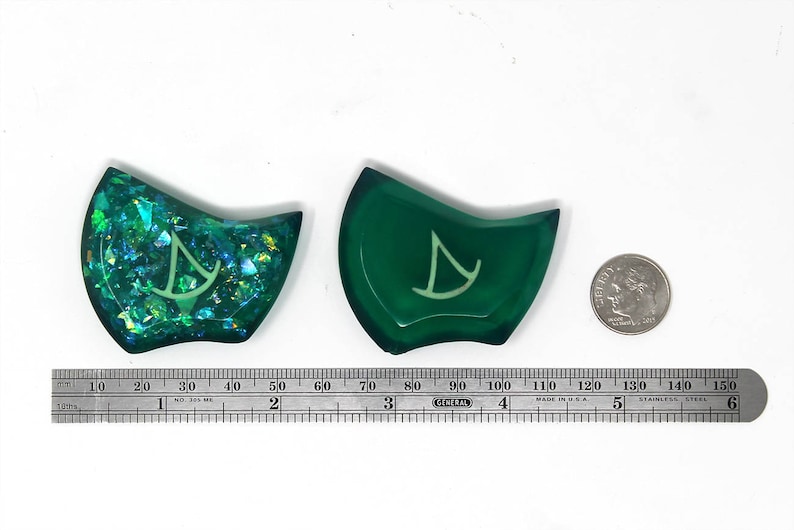 May include: Two green resin dice with a white symbol on each. One die has a glittery finish.