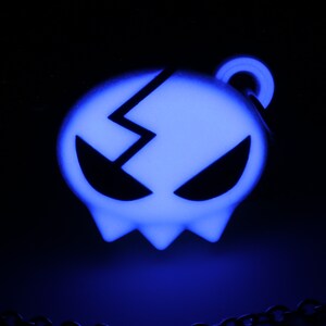 May include: A blue glow-in-the-dark skull pendant with a cracked design. The pendant is attached to a silver chain.