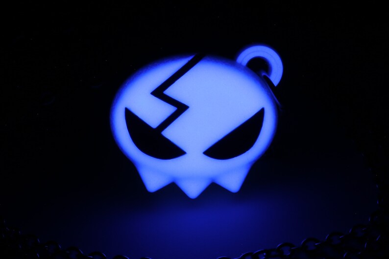May include: A blue glow-in-the-dark skull pendant with a cracked design. The pendant is attached to a silver chain.
