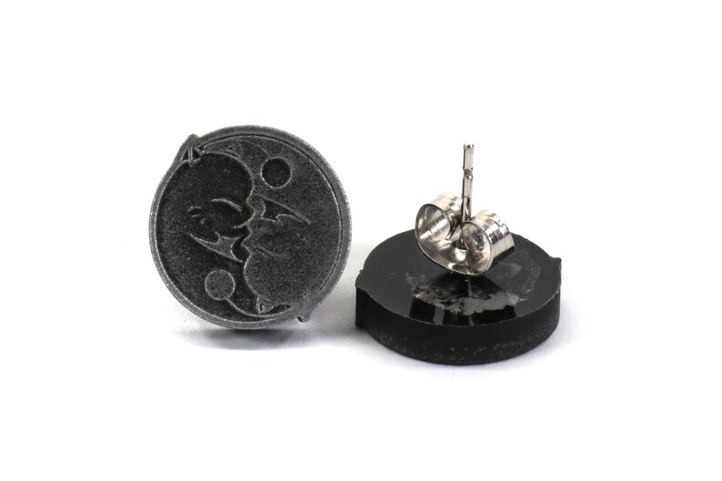 May include: A pair of silver stud earrings with a black and white yin yang symbol design. The earrings are made of metal and have a post back.