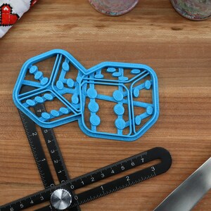 May include: Two blue plastic cookie cutters shaped like dice. The dice are joined together and have a textured surface.