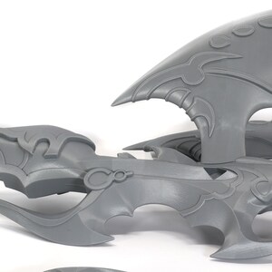 Peut inclure: Mod&egrave;le d'arme fantastique imprim&eacute; en 3D en plastique gris avec des d&eacute;tails complexes. L'arme est compos&eacute;e de plusieurs pi&egrave;ces, dont une lame, une poign&eacute;e et une pi&egrave;ce d&eacute;corative.