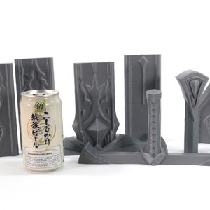 May include: A set of gray 3D printed pieces that can be assembled into a sword. The pieces are arranged on a white surface with a can of Japanese beer in the center.