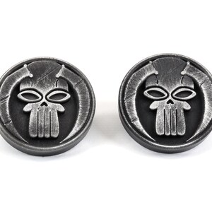 May include: Two silver-toned metal cufflinks featuring a skull design with horns. The skull has a detailed design with a textured surface.