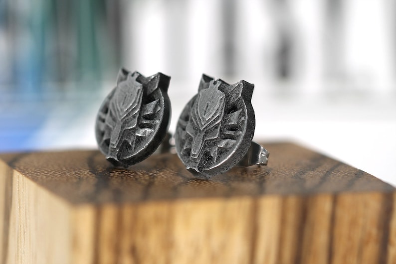 Op de afbeelding: Een paar zilveren oorbel studs met een gedetailleerd wolfskop ontwerp.