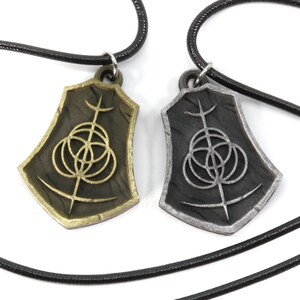 May include: Two necklaces with matching pendants. The pendants are shield-shaped with a black and silver design. One pendant is gold and the other is silver.