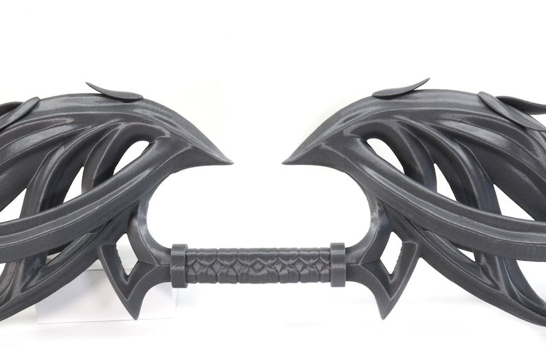 May include: A 3D printed, gray, decorative sword with a detailed, intricate design. The sword has a long, thin handle and two large, curved blades.