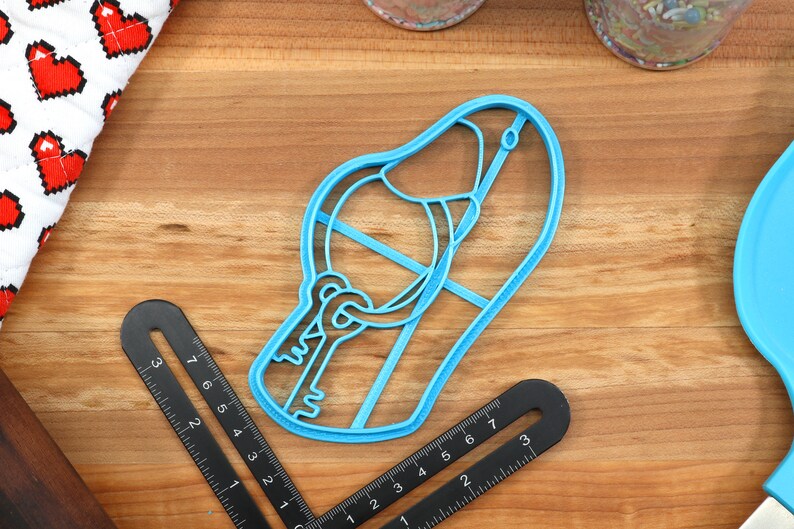 May include: A blue plastic cookie cutter shaped like a slipper with a keyhole and key design.