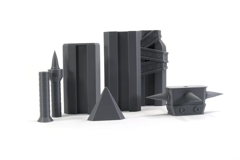 May include: A set of six grey 3D printed objects, including a pyramid, two spiky towers, a rectangular block, a tall rectangular block with a textured surface, and a spiky anvil.