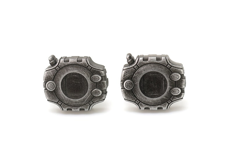 May include: A pair of silver cufflinks shaped like a digital watch with a black screen. The cufflinks have a detailed design with a textured surface.