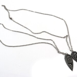 May include: Two silver chains with matching pendants. Each pendant is a silver teardrop shape with a detailed design of a mythical creature.