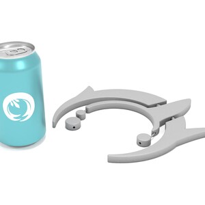May include: A light blue beverage can with a white logo and a silver top. Next to it are two gray drink holders with a dolphin-like design, along with two small gray circular pieces. The items are on a white background.