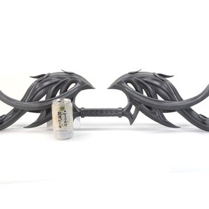 May include: A gray, intricately designed, double-ended weapon with a long, thin handle. The weapon is about the size of a standard aluminum can.
