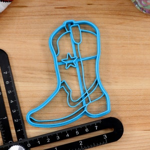May include: A blue plastic cowboy boot cookie cutter with a star design.