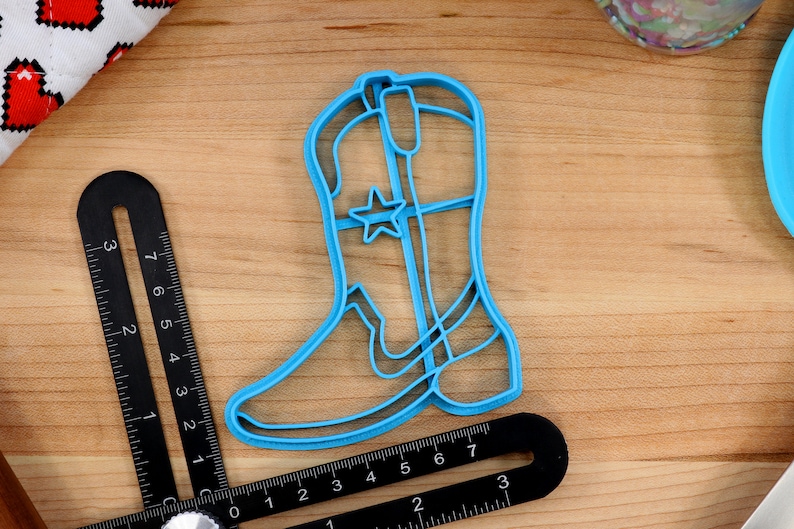 May include: A blue plastic cowboy boot cookie cutter with a star design.
