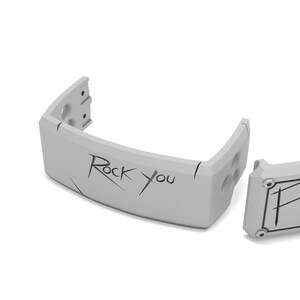 May include: A light gray wristband with the words "Rock You" and "FREE" etched in black. The wristband is segmented, with a curved design and visible screw holes. The background is plain white.