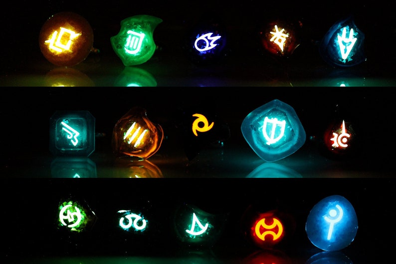 May include: A set of 15 glowing resin dice with various symbols and colors, including blue, green, orange, and red. The dice are arranged in three rows of five.