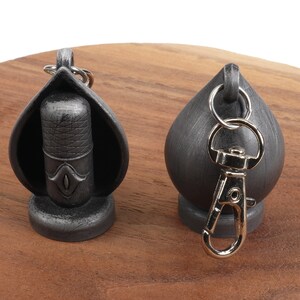 May include: Two silver keychains, one with a microphone design and the other with a round shape. Both keychains have a silver metal ring.