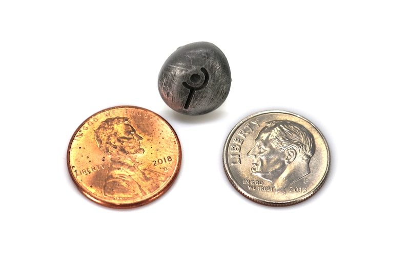 May include: A silver metal bead with a rune symbol engraved on it. The bead is about the size of a dime.